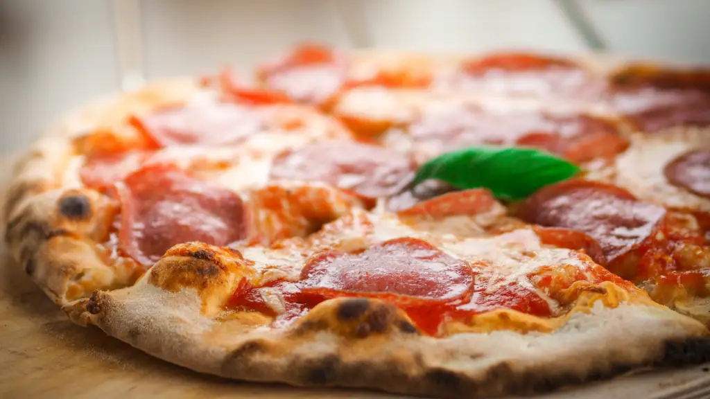 En glutenfri pepperoni-pizza med sprød skorpe, smeltet ost, tomatsauce og et frisk basilikumblad på toppen.